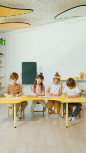 Children learning together at a table in a bright classroom setting.